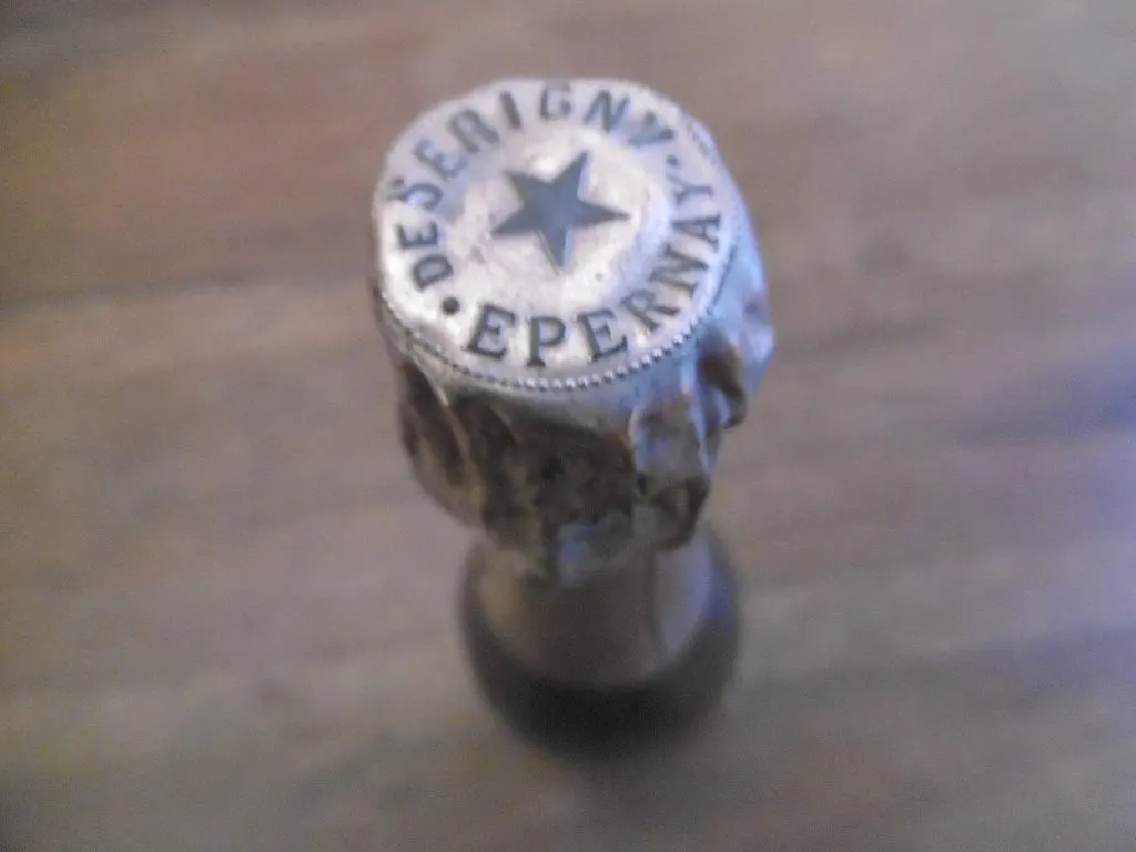 Bouchon d'une bouteille ancienne coiffé d'une plaque marquée De Serigny Epernay avec une étoile