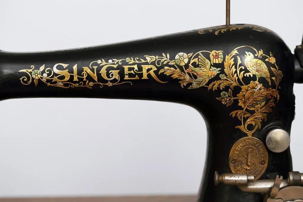 Bras noir d'une machine à coudre Singer modèle 27 avec inscription SINGER dorée et décor floral à l'oiseau