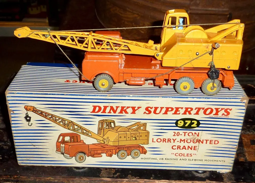 Camion grue Dinky Supertoys 972 orange et jaune posé sur sa boîte rayée bleu et blanc