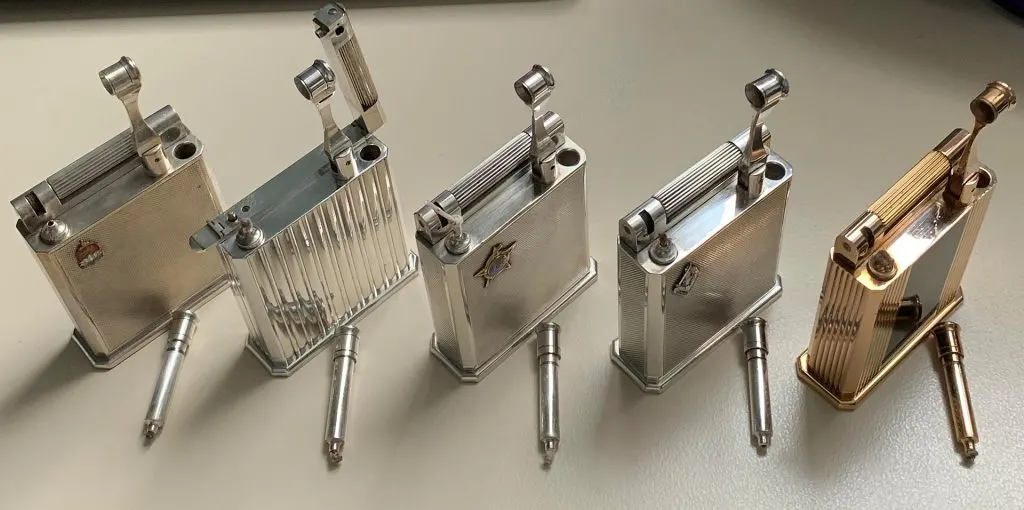 Cinq briquets de table S.T. Dupont Jéroboam à essence, métal argenté et doré, alignés