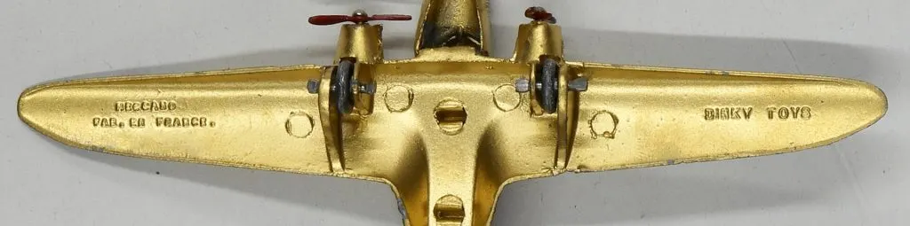 Dessous doré d'un avion miniature Dinky Toys portant les mentions Meccano et Fab. en France