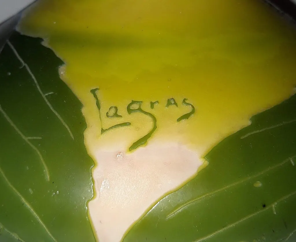 Gros plan de la signature Legras dégagée en camée vert à l'acide parmi des feuilles, à la base d'un vase