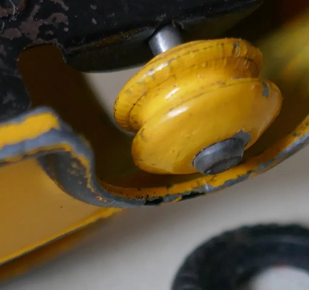 Gros plan d'une jante jaune de Dinky Toys sous le châssis, sans pneu