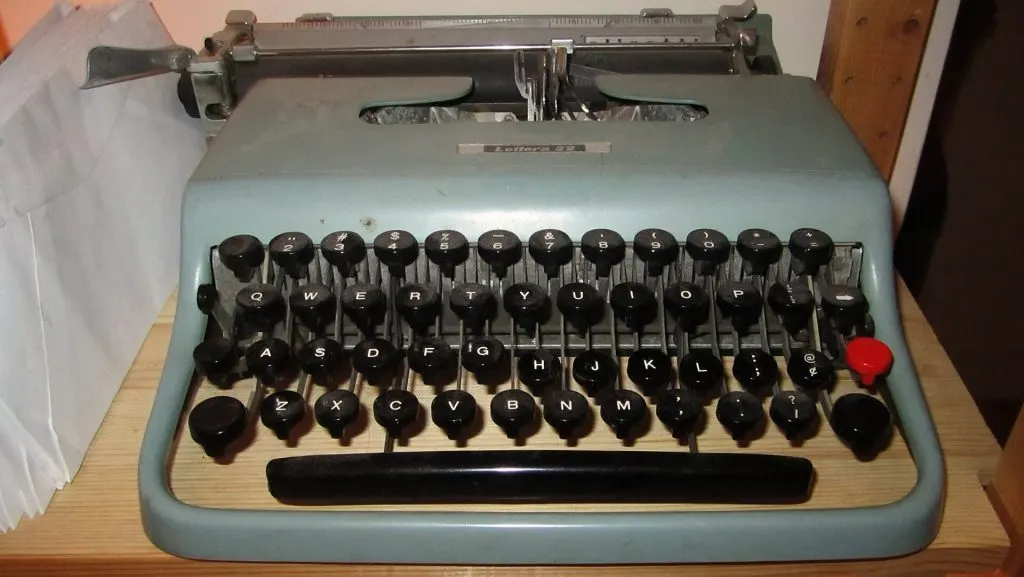 Machine à écrire portable Olivetti Lettera 22 vert d'eau avec touches rondes noires, posée sur une table