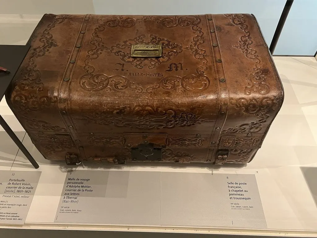 Malle de voyage bombée en cuir brun gaufré de rinceaux, avec poignée et serrure, au musée de La Poste