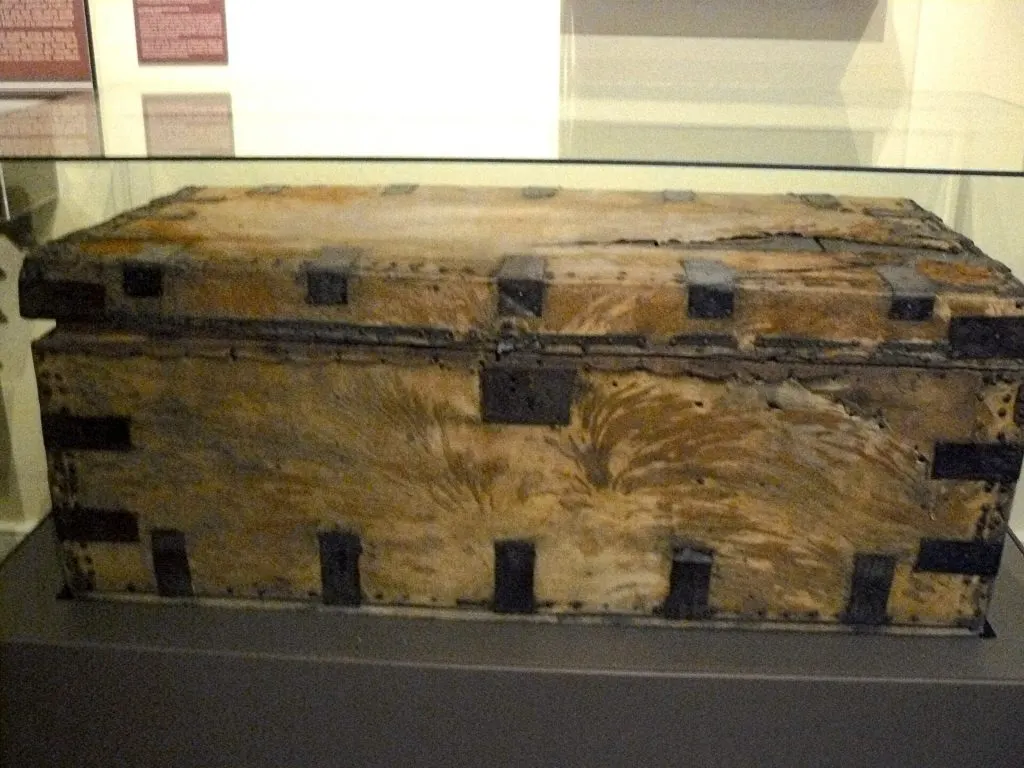 Malle du XIXe siècle recouverte de peau, renforcée de ferrures noires, exposée sous vitrine