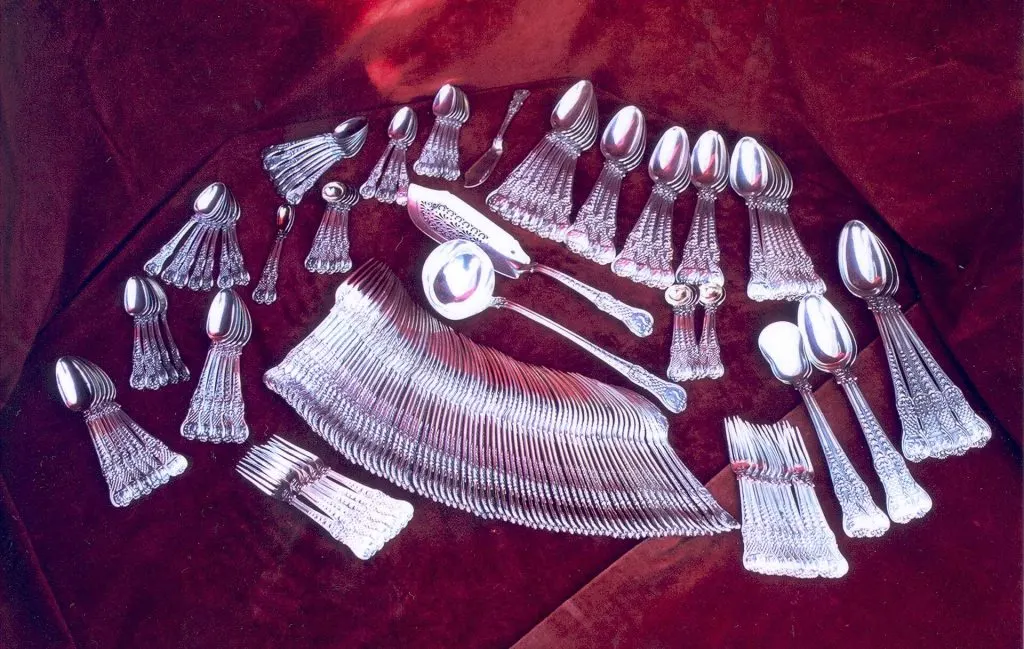 Ménagère de couverts en argent disposée en éventail sur un velours rouge