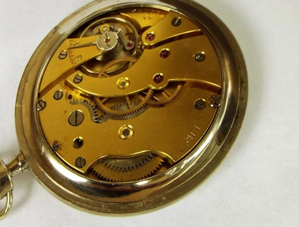 Mouvement mécanique d'une montre de poche Lip en boîtier doré, ponts gravés LIP, vu par le fond ouvert