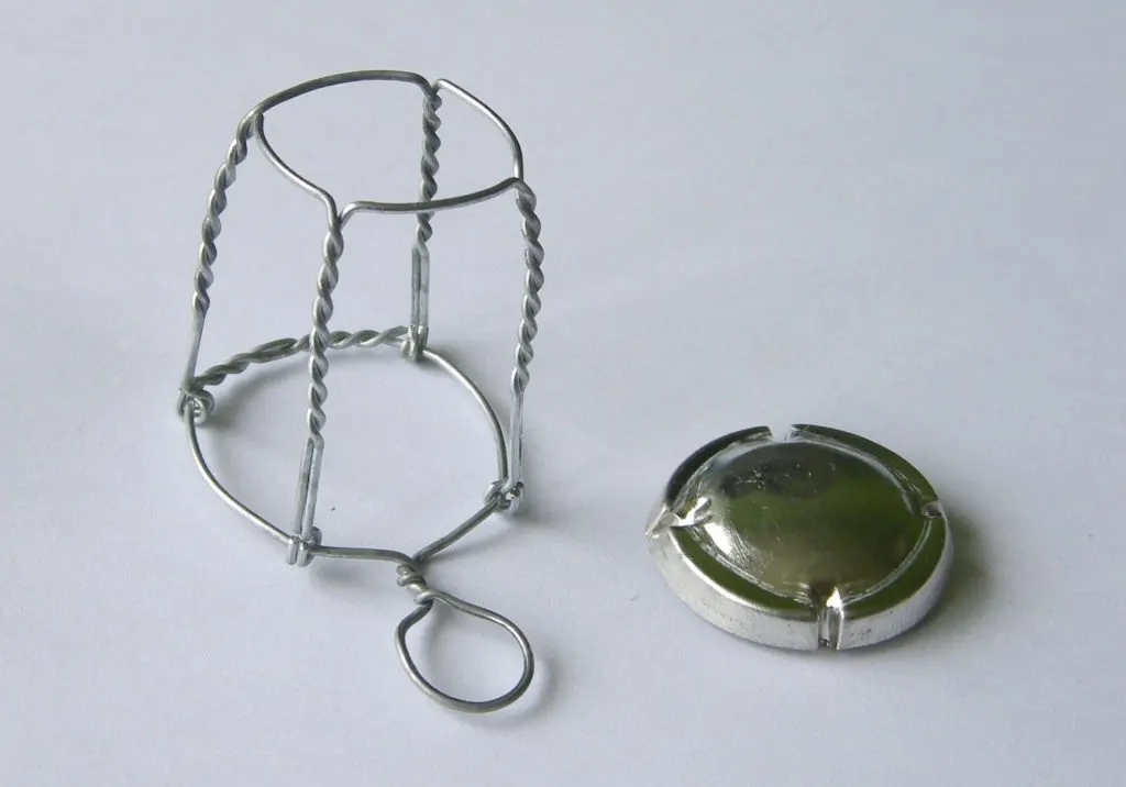 Muselet en fil de fer torsadé posé à côté de sa plaque métallique ronde
