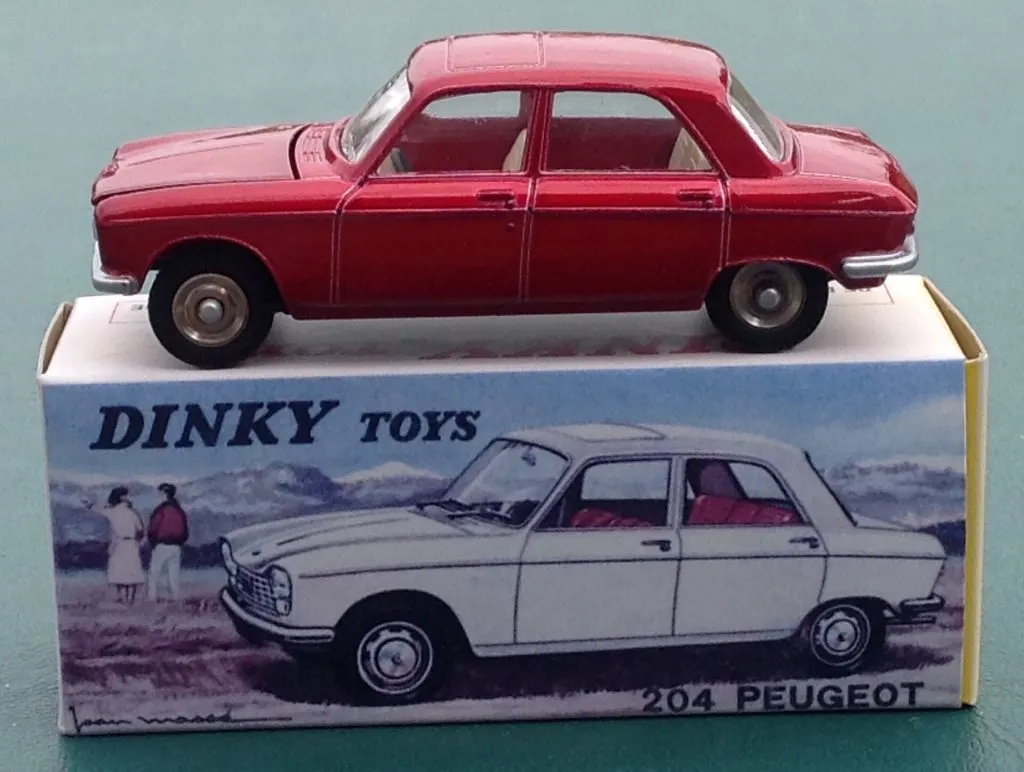 Peugeot 204 rouge miniature, réédition Atlas des Dinky Toys, posée sur sa boîte illustrée