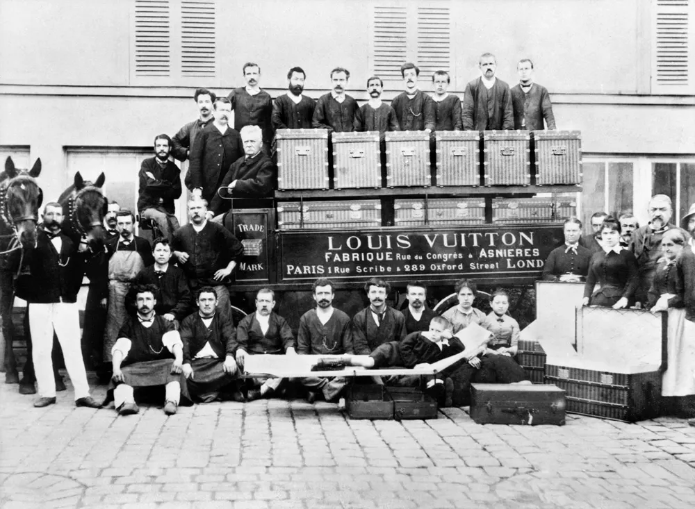 Photo ancienne des ouvriers Vuitton posant devant une voiture de livraison chargée de malles à Asnières