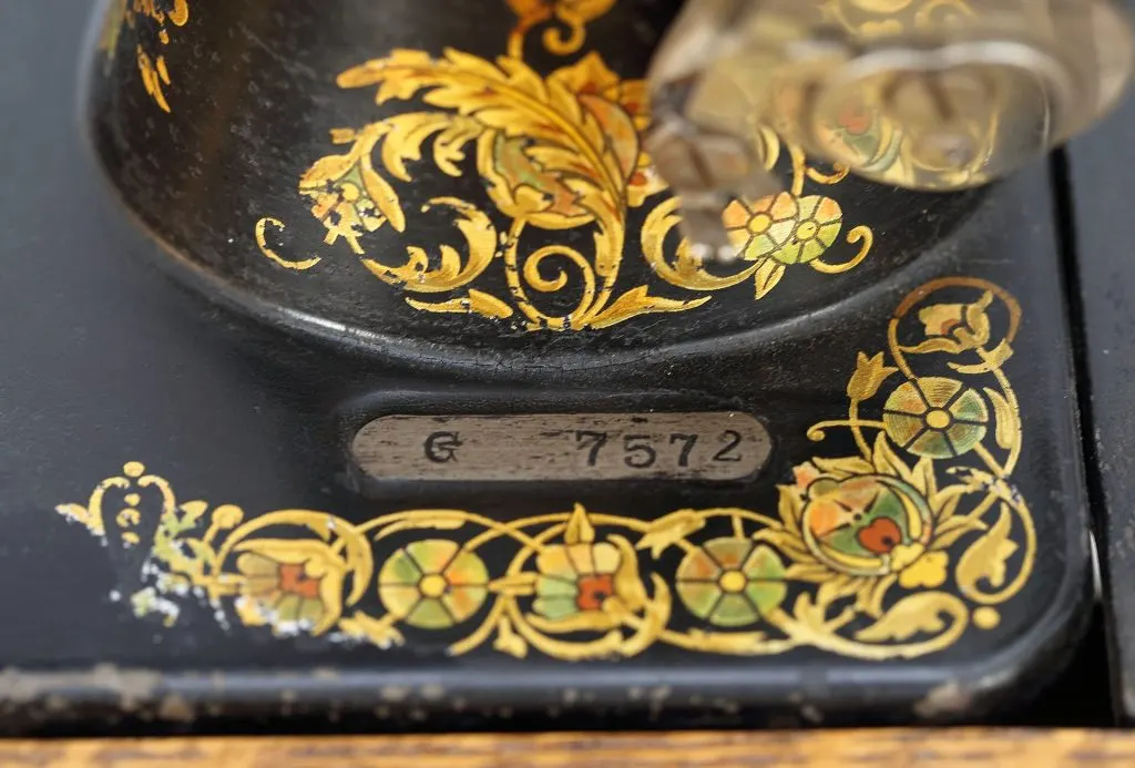 Plaque de numéro de série G 7572 sur le plateau noir à décor doré d'une machine Singer modèle 27