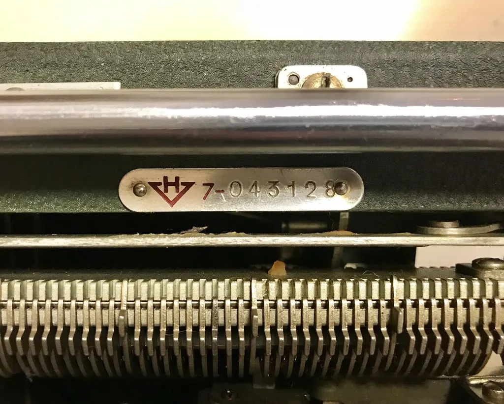 Plaquette métallique portant le numéro de série 7-043128 sous le chariot d'une machine à écrire