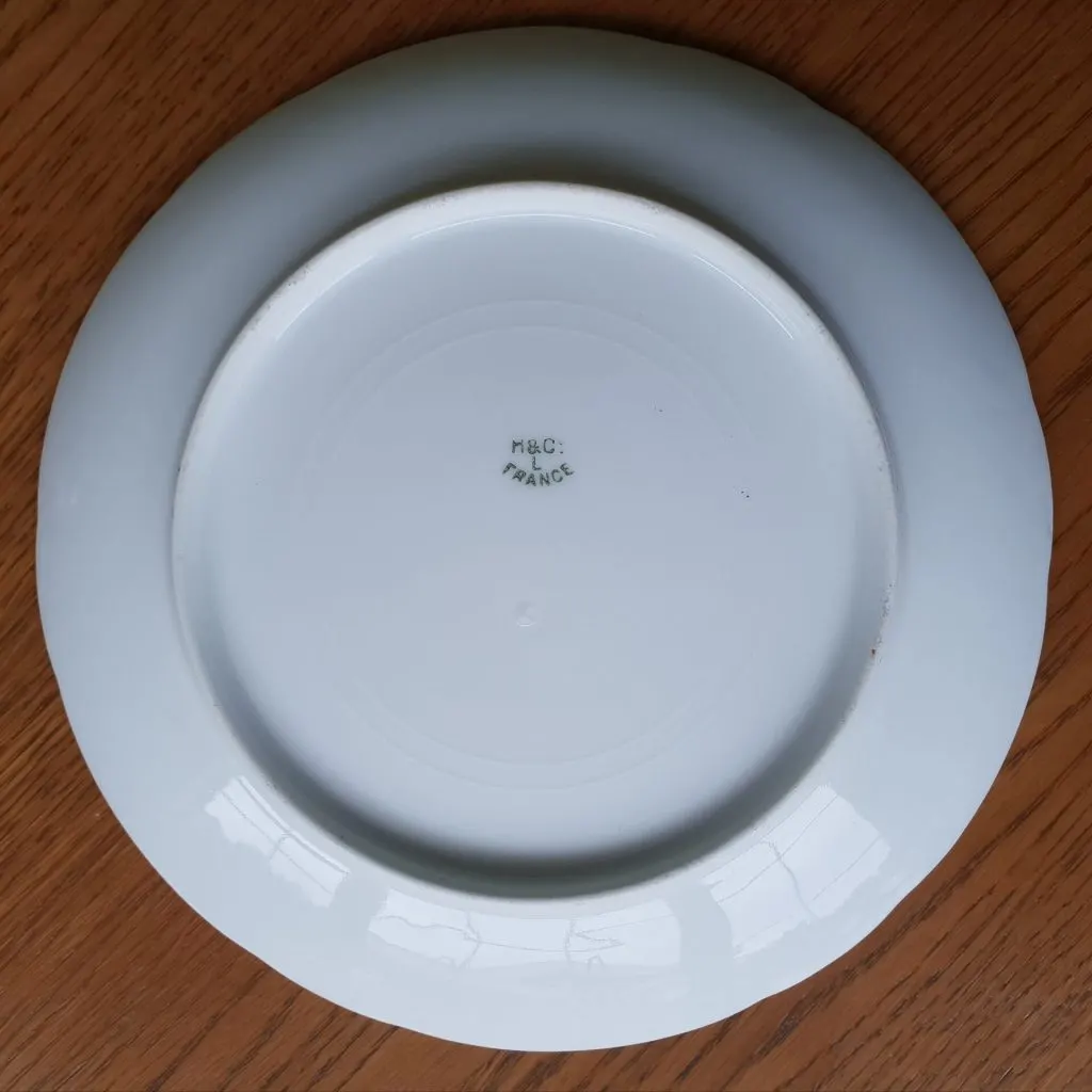 Revers blanc d'une assiette Haviland à bord festonné avec une petite marque imprimée au centre