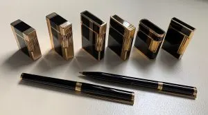 Six briquets S.T. Dupont plaqué or et laque de Chine noire alignés devant deux stylos assortis