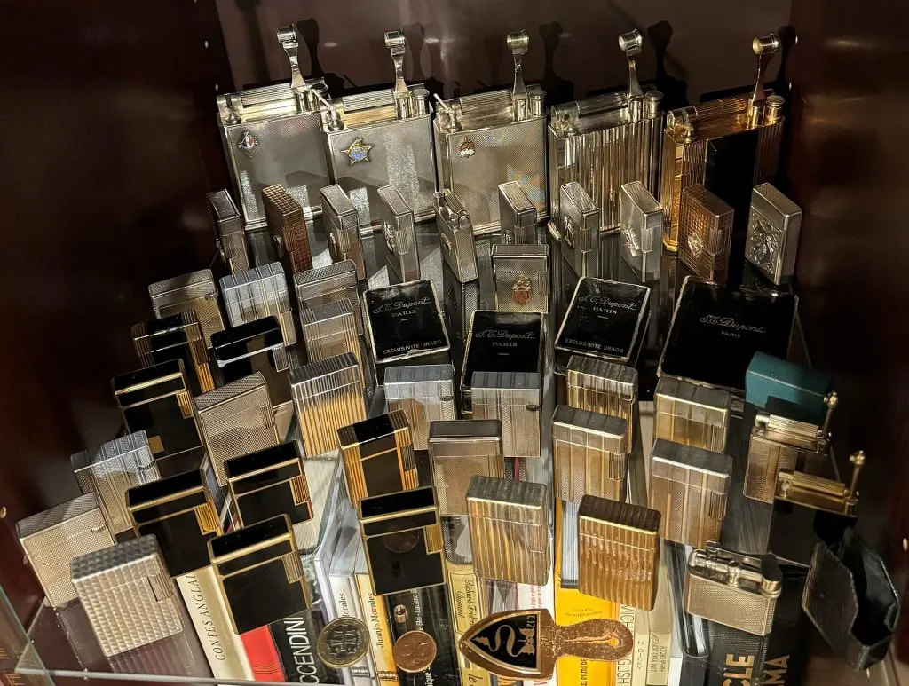Vitrine de collectionneur remplie de briquets S.T. Dupont à essence argentés, dorés et laqués